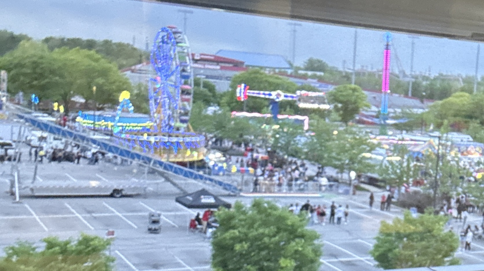 Some carnival rides outside with lots of people.